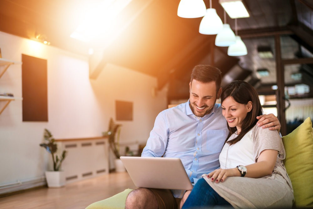 Couple smiling while shopping online at home